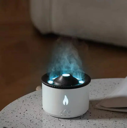 An ultrasonic essential oil humidifier with a volcano-like pattern emitting mist, illuminated by an artificial flame light.