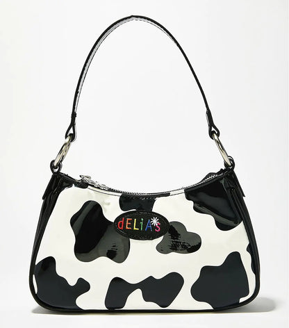 A black and white cow print baguette bag with a woman's hand holding it, displayed in front of a white background with the text 'POE LAND'.