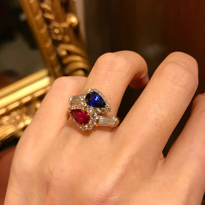 A vintage two-tone brushed ring with a drop-shaped design, featuring blue and red colors, placed on a person's finger.