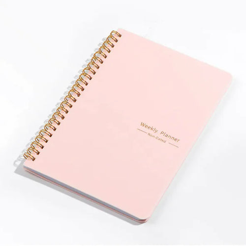 A pink weekly schedule notebook with a spiral binding and the text 'Weekly Planner' printed on the cover.